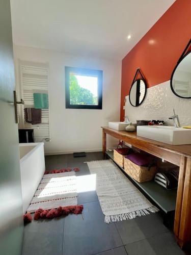 une salle de bain avec un lavabo, une baignoire et un miroir dans l'établissement Maison en bois au calme piscine, à Corbarieu