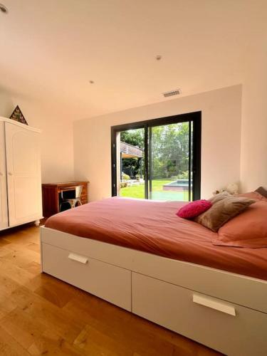 une chambre avec un grand lit avec une grande fenêtre dans l'établissement Maison en bois au calme piscine, à Corbarieu