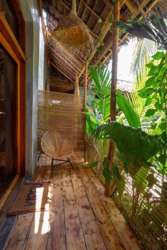 a room with a rattan chair on a wooden floor at The Garten Living in Paje