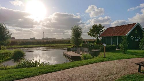 a green building next to a river with a boat at Habbo's Kojen in Neuharlingersiel