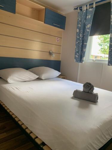un lit avec un animal rembourré assis au-dessus dans l'établissement Coquet mobilhome climatisé, à Villeneuve-lès-Maguelone