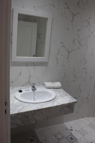 a white bathroom with a sink and a mirror at Hôtel Medina in Sousse