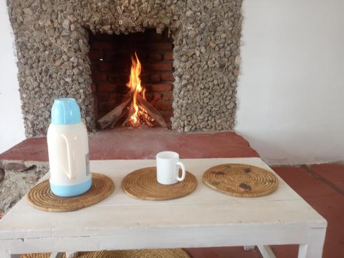 un tavolo con due tazze e una bottiglia di latte e un camino di Eco Farm a Karatu
