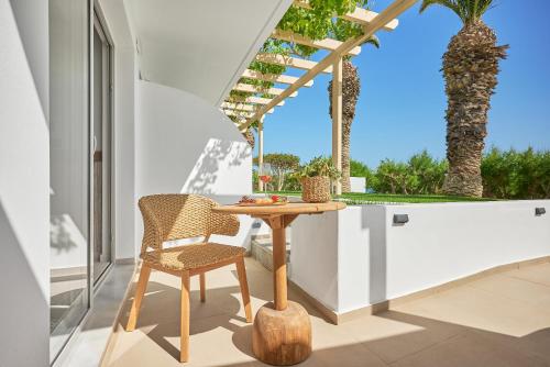 a table and chair on a balcony with a palm tree at Artemis in Makry Gialos
