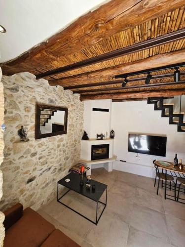 a living room with a tv and a stone wall at Rafeio Roustic Maisonette in Episkopi (Heraklion)