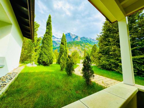a view of a yard with trees and mountains at Amazing Modern & Great equipped Jacuzzi Apartment in Kandersteg