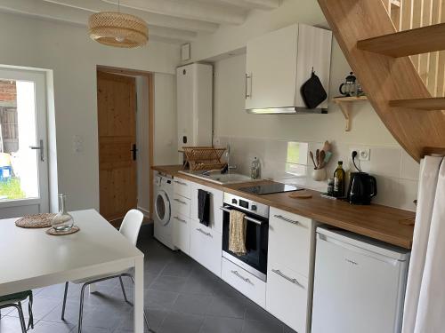 une cuisine avec des appareils blancs, une table et une table ainsi qu'une salle à manger dans l'établissement Petite maison Duplex, à Aubigny-sur-Nère