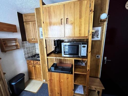 La cuisine est équipée de placards en bois, d'un four micro-ondes et d'un four micro-ondes. dans l'établissement Résidence Dorons - Studio pour 2 Personnes 104, aux Menuires