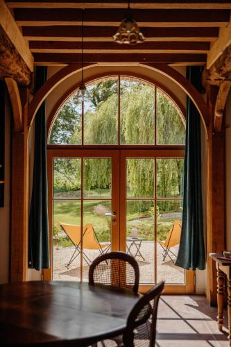 a dining room with a table and a large window at Les Bucoliques de la Noë in Goven