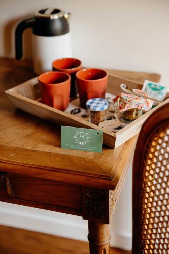 a tray with cups on top of a wooden table at Les Bucoliques de la Noë in Goven
