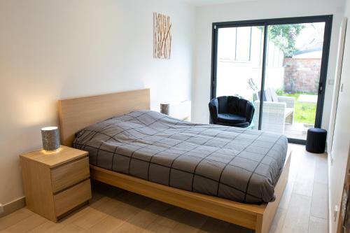 a bedroom with a bed and a chair and a window at Residence VELOURS avec terrasse , jardin et parking in Champigny-sur-Marne