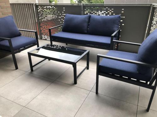 trois chaises bleues et une table basse sur un balcon dans l'établissement Appart de luxe au design moderne, à Bezons