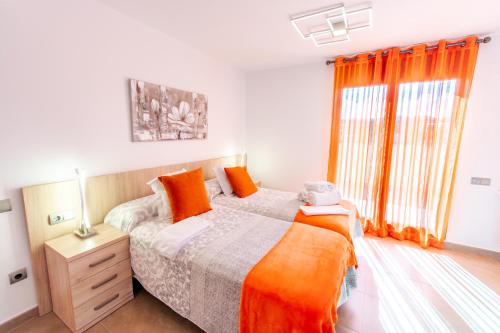 a bedroom with a bed with orange pillows and a window at Casa Tío Pepe Valderrobres in Valderrobres