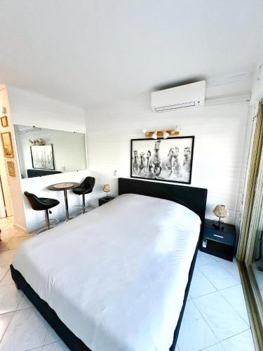 une chambre avec un grand lit blanc et une table dans l'établissement #T03 DUCAL MARINA BAIE DES ANGES avec Terrasse, à Villeneuve-Loubet