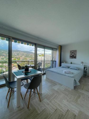 une chambre avec un lit et une table avec des chaises dans l'établissement Cannes Marina Résidence Le Surcouf - Studio de 28m2 au 10ème étage avec piscine, terrasse, parking, vue montagne et port : Mandelieu-La Napoule, à Mandelieu-la-Napoule