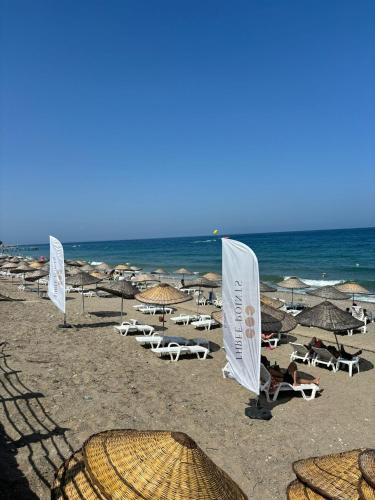 a beach with umbrellas and chairs and the ocean at Three Points Hotel in Beldibi