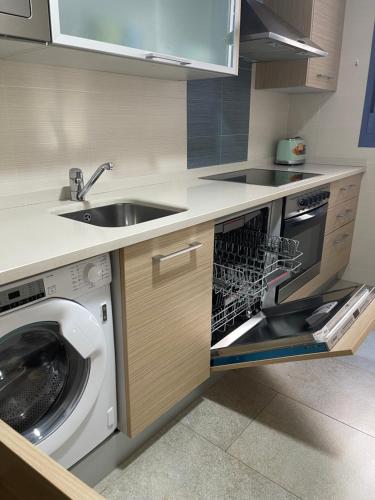 a kitchen with a washing machine in a dishwasher at Apartamento Augusta Cambrils Lux con vista al mar in Cambrils
