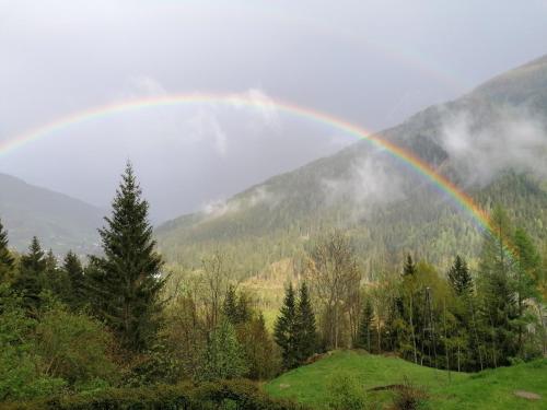 a rainbow in the middle of a field with trees at Ferienwohnungen Rabensteiner in Bad Kleinkirchheim