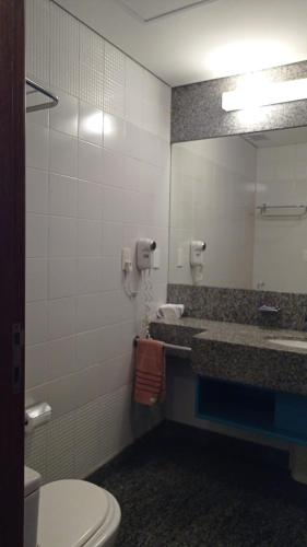 a bathroom with a sink and a toilet and a mirror at Flat BH Savassi in Belo Horizonte