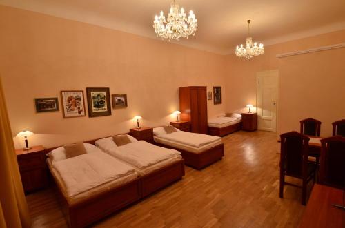 a bedroom with two beds and a dining room with chandeliers at Pension Karlova in Prague