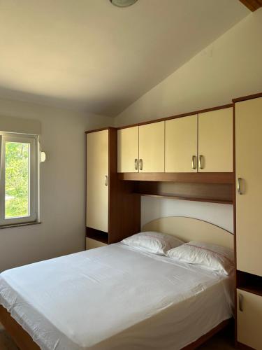 a bedroom with a large white bed with cabinets at Apartments Anka Brala in Posedarje