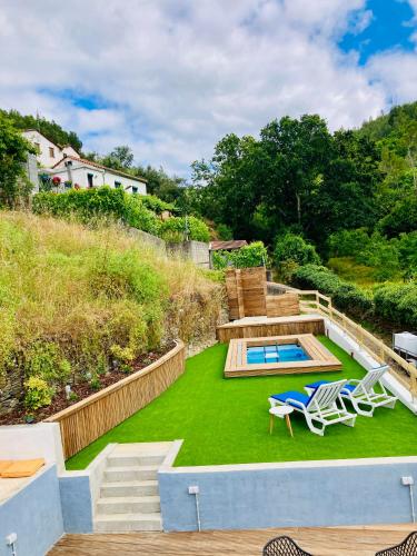 a backyard with a lawn with two chairs and a pool at Casa SuasDuas in Vila Cova de Alva