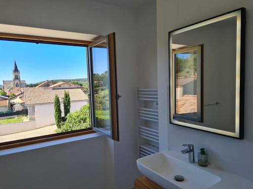 La salle de bains est pourvue d'un miroir, d'un lavabo et d'une fenêtre. dans l'établissement La maison des Remparts, à Clérieux