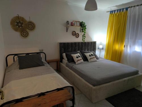 a bedroom with two beds and a yellow curtain at 4 Seasons Apartment in Leskovik