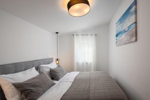 a bedroom with a bed in a white room at Villa Mala Smišna Poolside Paradise by the Sea in Maslinica