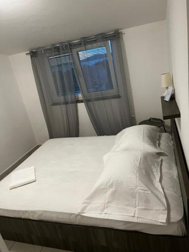 a bedroom with a white bed with a window at Amfora in Bibinje