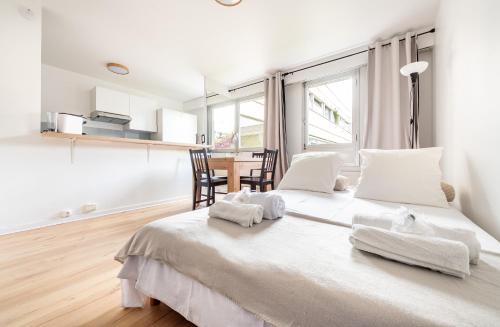 - une chambre blanche avec un grand lit et des serviettes dans l'établissement Montparnasse & Studio & Downtown, à Paris