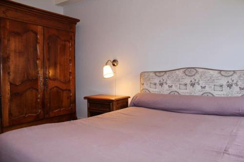 une chambre avec un lit et une armoire en bois dans l'établissement Domaine du Lacarès, à Saint-Magne-de-Castillon