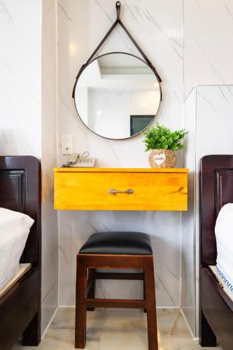 a bathroom with a vanity with a mirror and a stool at Mai Phương - RUBY SAIGON HOTEL in Ho Chi Minh City