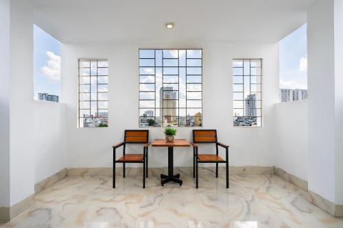 a table and two chairs in a room with windows at Mai Phương - RUBY SAIGON HOTEL in Ho Chi Minh City