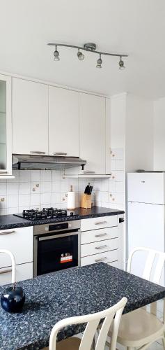 une cuisine avec des armoires blanches et une table avec des chaises dans l'établissement Logement au bord de la Seine, proche de Paris, à Épinay-sur-Seine