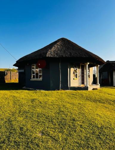 una piccola casa con un tetto in erba su un campo di Mbotyi Mnceba cottage a Lusikisiki