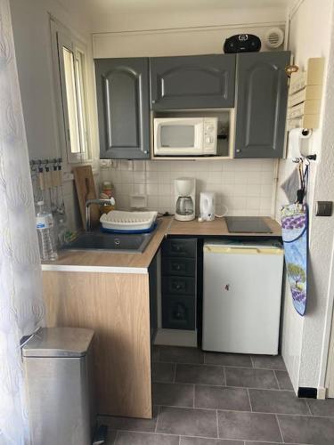 Elle comprend une petite cuisine avec des placards noirs et un réfrigérateur blanc. dans l'établissement Appartement T2 proche mer, à Canet