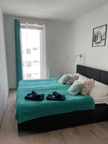 a bedroom with a bed with green sheets and a window at Fonyódi Fészek in Fonyód