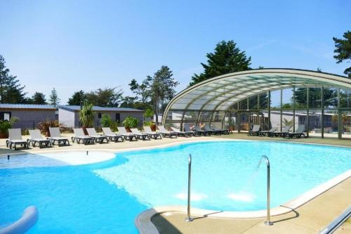 une grande piscine avec des chaises et un bâtiment dans l'établissement Cottage 4-6 pers-piscine chauffée-150m plage, à Jullouville