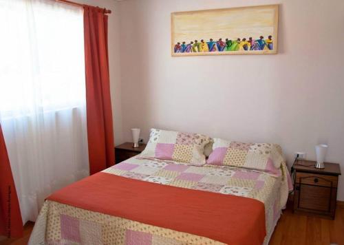 1 dormitorio con 1 cama y una pintura en la pared en Hostal Alto Algarrobal, en Combarbalá