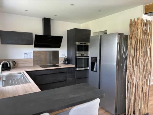 eine Küche mit einem Kühlschrank aus Edelstahl und einer Spüle in der Unterkunft Jolie maison proche plages et golf in Bénodet