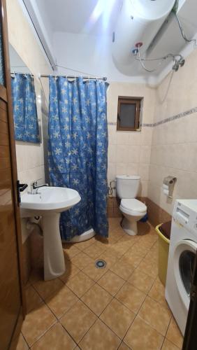 a bathroom with a toilet and a sink and a washing machine at Bega Apartment in Sarandë
