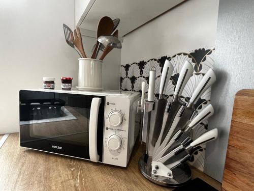 une cuisine avec un micro-ondes et un tas d'ustensiles dans l'établissement Charmante maison de ville avec jardin, à Le Petit-Quevilly