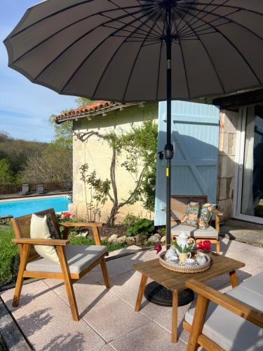 a patio with a table and an umbrella at La Colline de Tilleul - De La Colline 4 STAR RATED - Beautiful Cottage Near Aubeterre in Saint-Romain