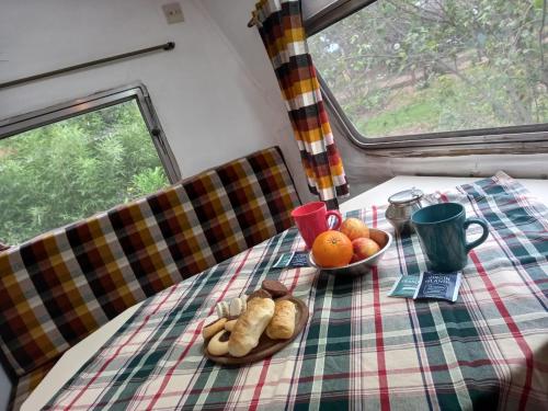シエラ・デ・ラ・ベンターナにあるTiny House Ventaniaのパン2皿と果物が入ったテーブル