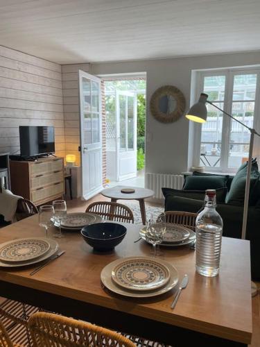 une table de salle à manger avec des assiettes et des verres dessus dans l'établissement Le Cabanon de Paulo - 350m Plage - Terrasse ext, à Étretat