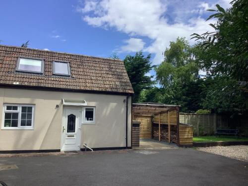 a white house with a garage and a fence at Selfcatering Coach House New Forest Dog Friendly in Ringwood