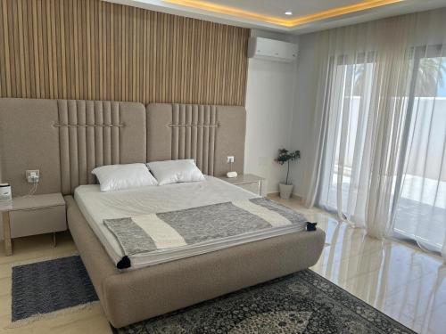 a bedroom with a large bed and a large window at Grande Villa Familiale Route Du Phare in Djerba