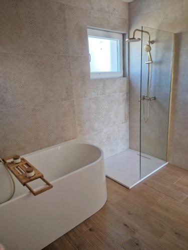 a bathroom with a tub and a shower with a window at Rustic House Konfidenca in Biograd na Moru