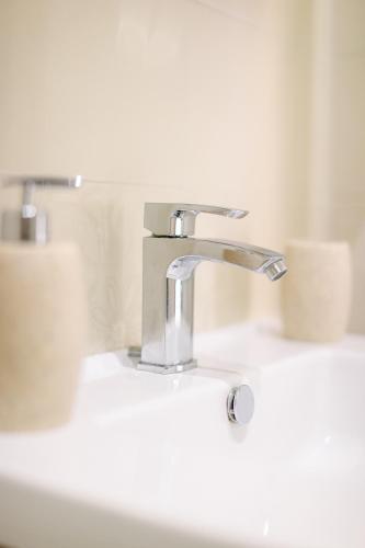 a bathroom sink with a silver faucet and two toilets at DOMUS Gallery in Naples